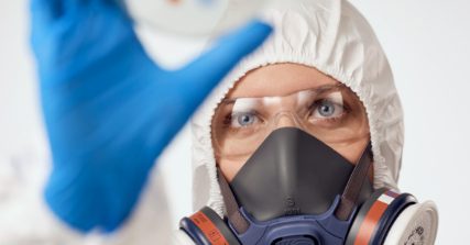 Woman in coveralls, protective glasses and respirator