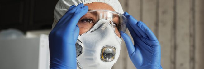 Woman in protective clothing putting on safety goggles